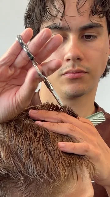 Liam Kolt carefully cutting a client’s hair with scissors